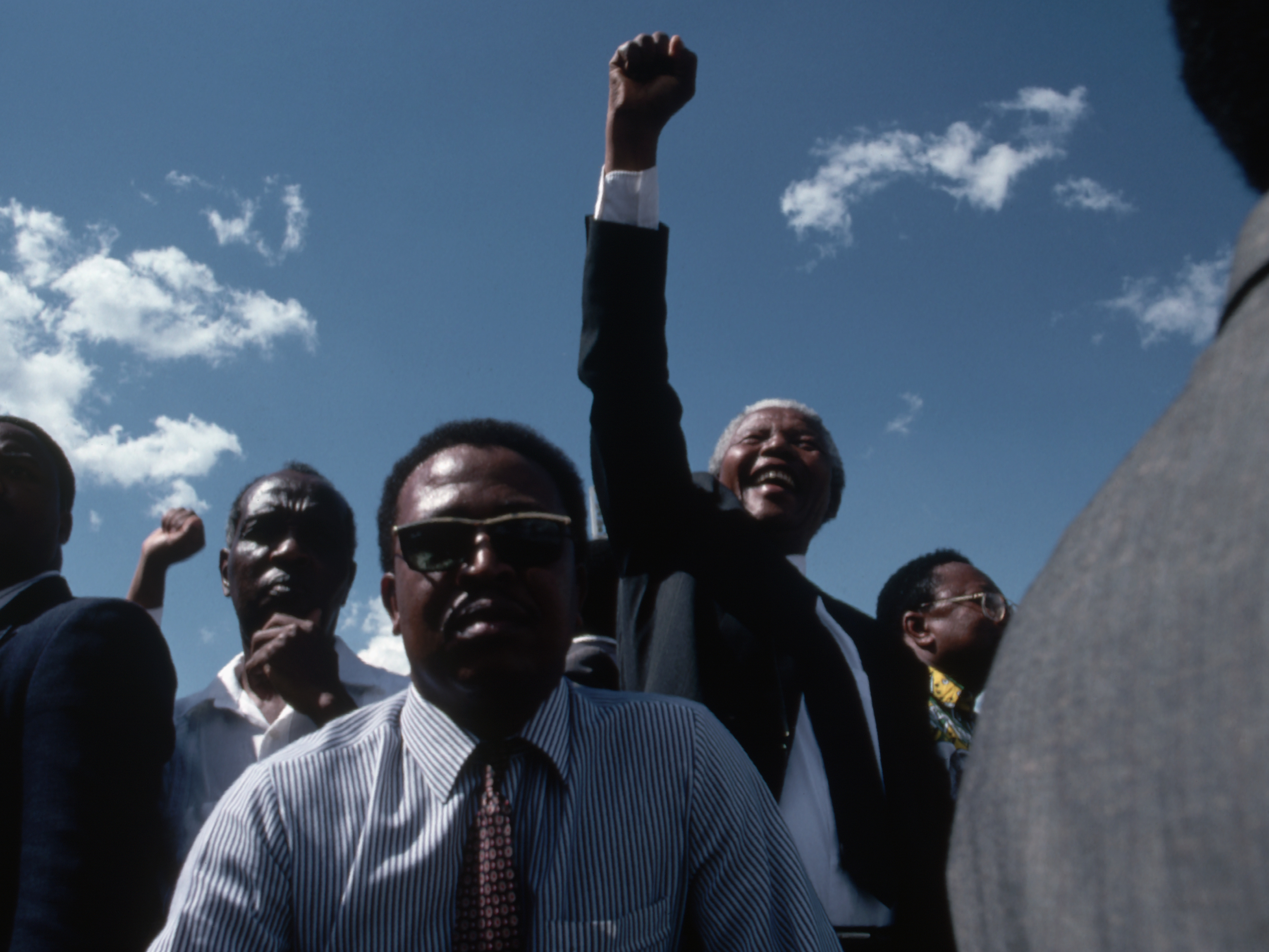 Bodyguards keep close watch as Nelson Mandela celebrates his victory in the South African presidential elections of 1994. As the head of the African National Congress, he helped to build the country